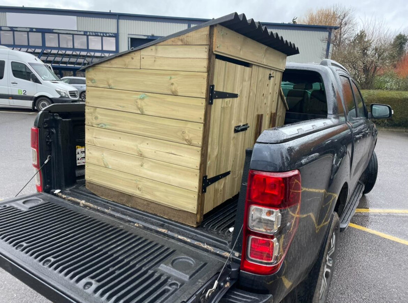 A coop being delivered in the back of a pickup truck.